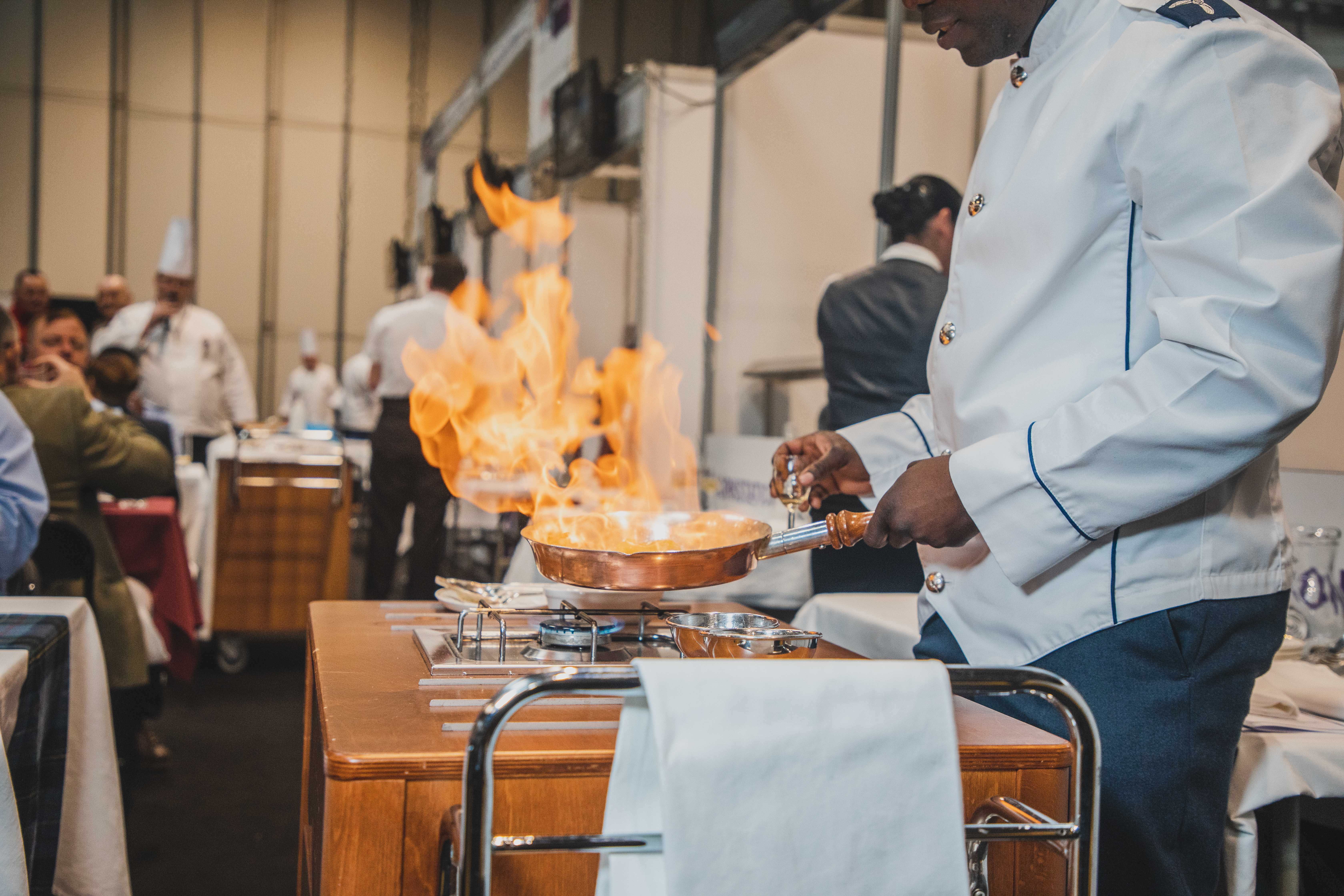 An RAF Caterer flambées a dish at Exercise Joint Caterer